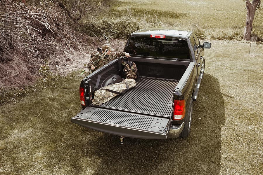 hunter placing bags in the back of a pickup truck with a duraliner in it